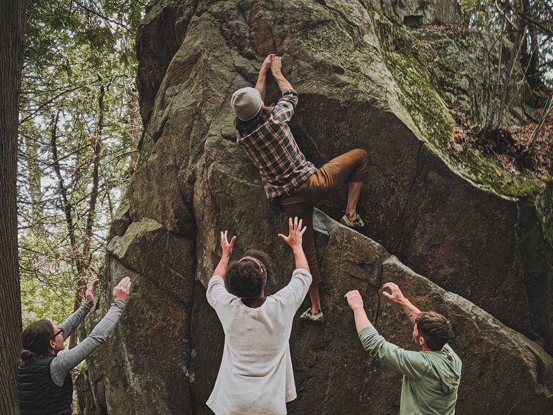 people helping men climb rock