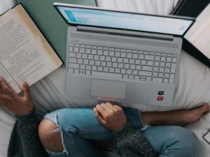 woman studying laptop books on bed