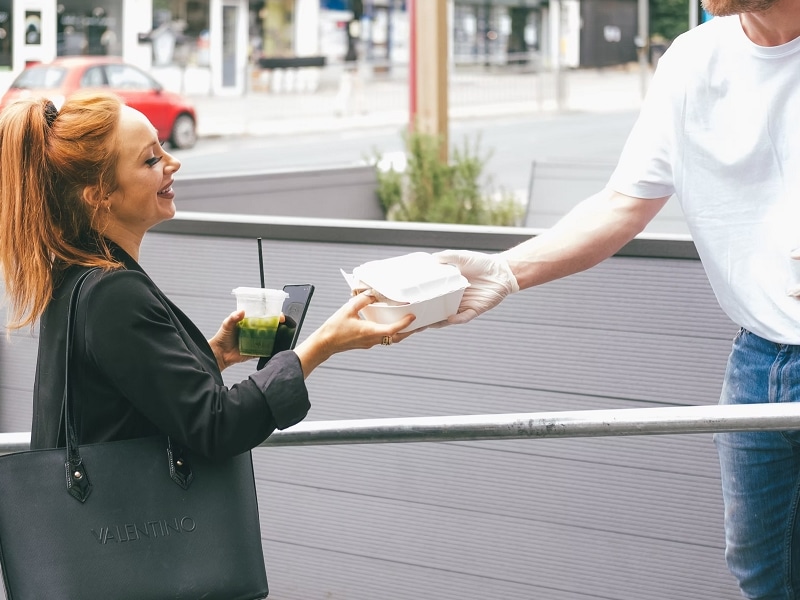 man handing woman food box smile