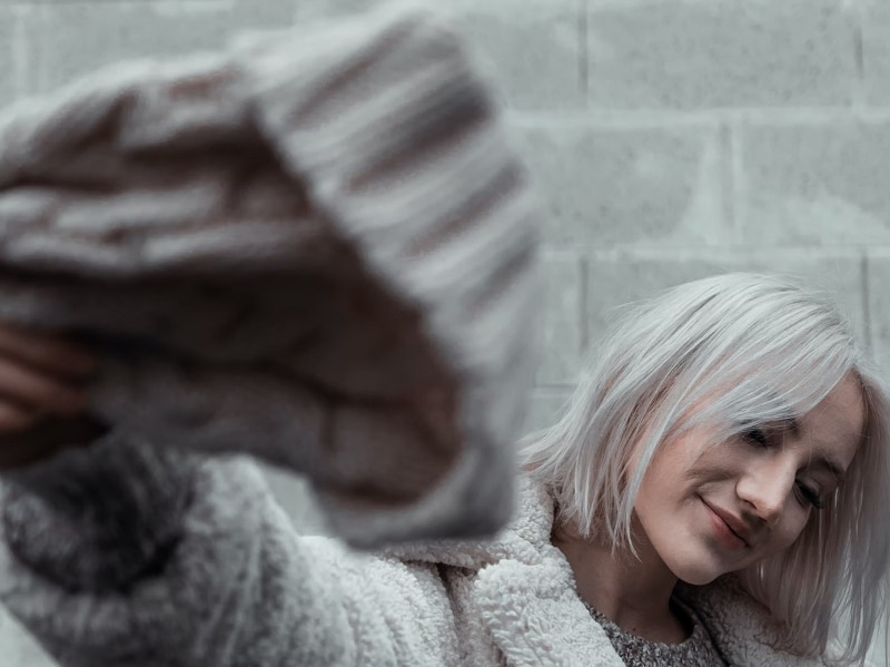 woman taking hat off smiling