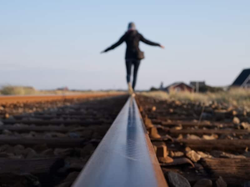 person balancing on train tracks