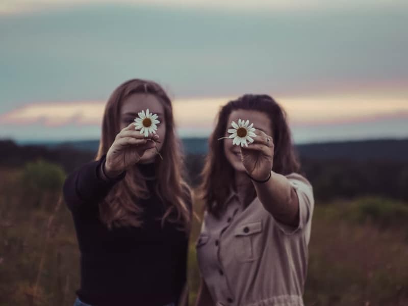 women holding flowers and smiling