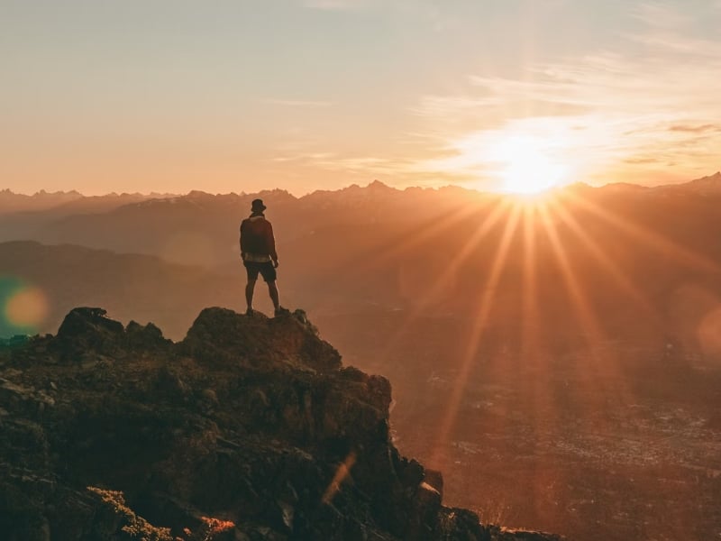 person on top of mountain at sunset