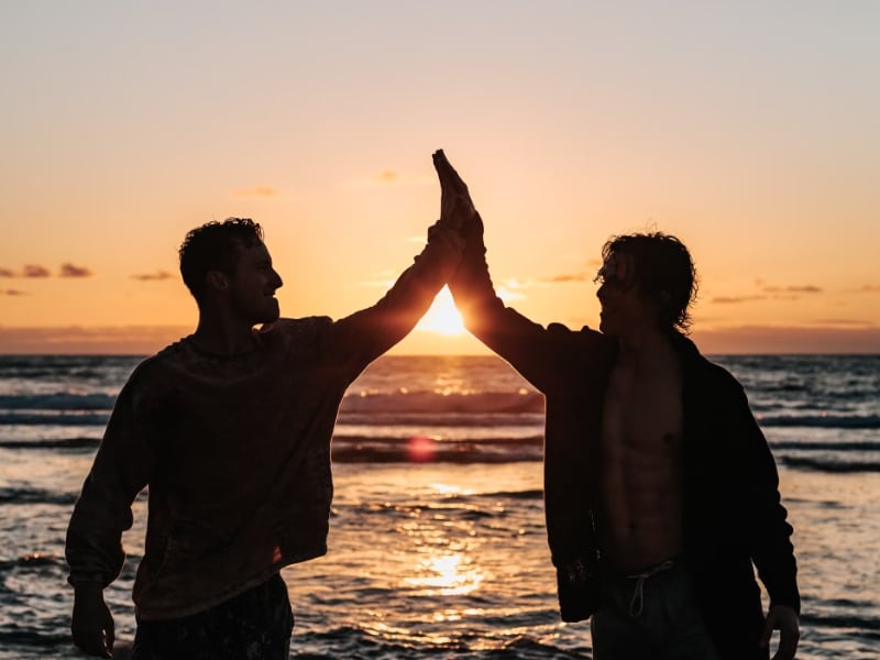 two men highfiving on beach