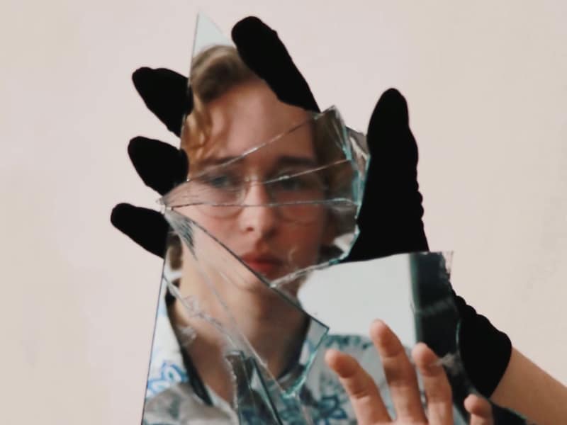 woman looking at reflection in broken mirror