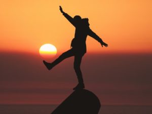 person balancing in front of sunset