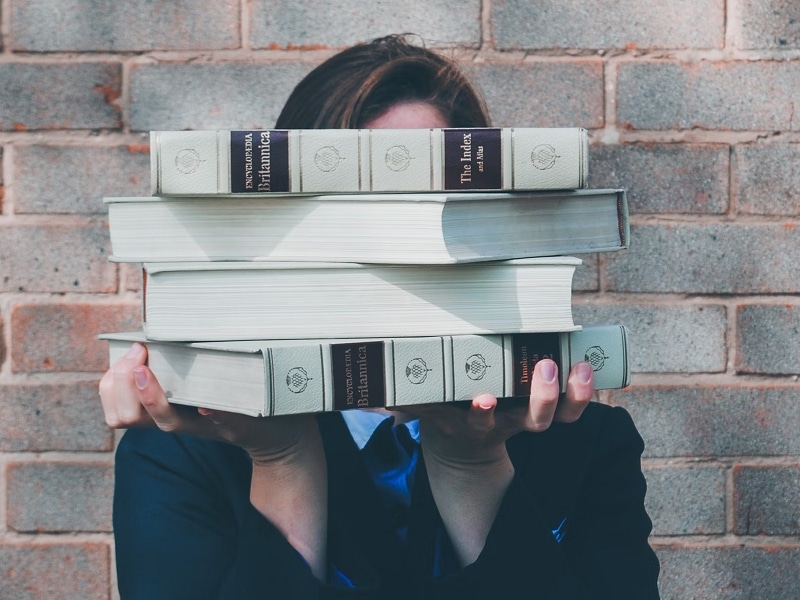 woman holding pile of books