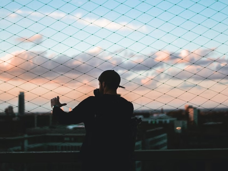 man standing behind fence