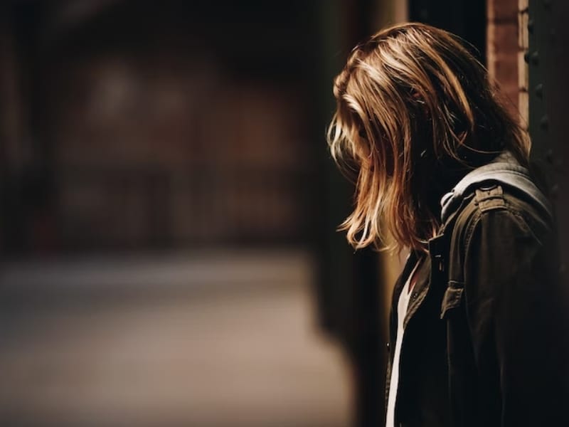 woman leaning against wall in darkness