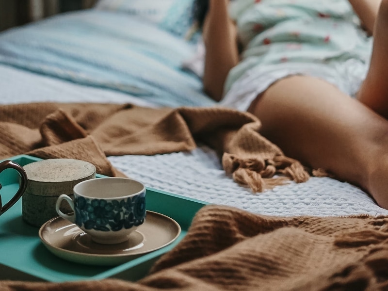 woman reading in bed with coffee and tea