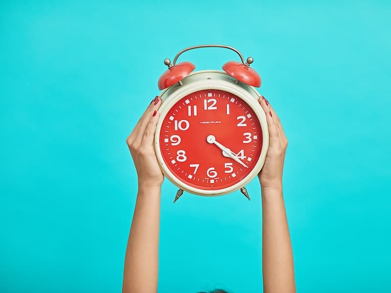 person holding up clock