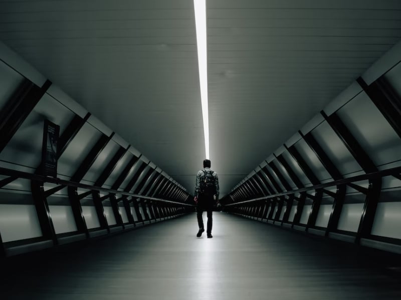 person walking in long dark hallway