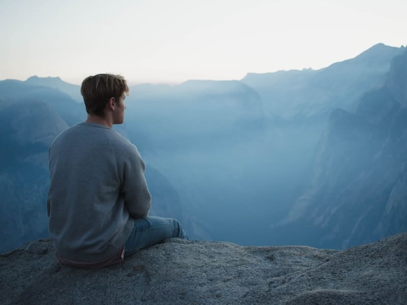 person sitting alone on cliff