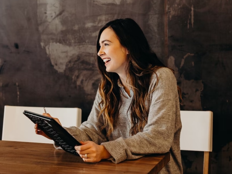 woman sitting at table with notepad laughing