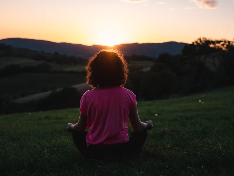 woman meditating outside at sunset