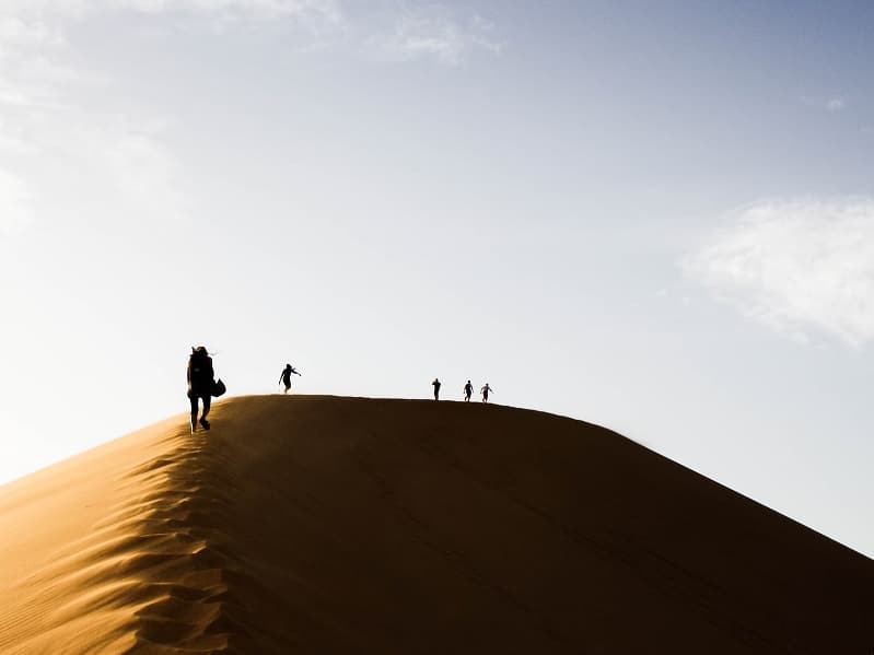 people climbing sand dune
