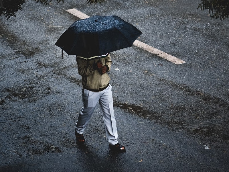 person walking in rain under umbrella