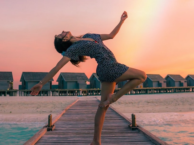 woman on dock dancing with rainbow