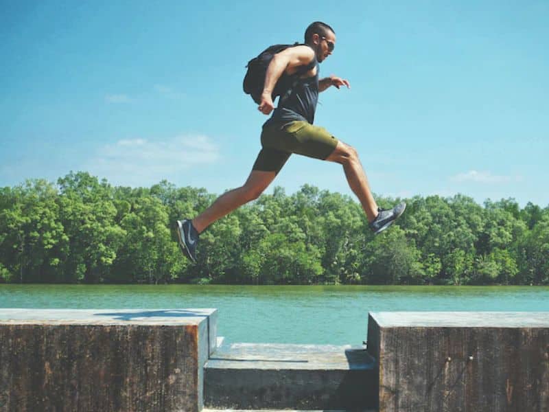 energetic man leaping between concrete blocks