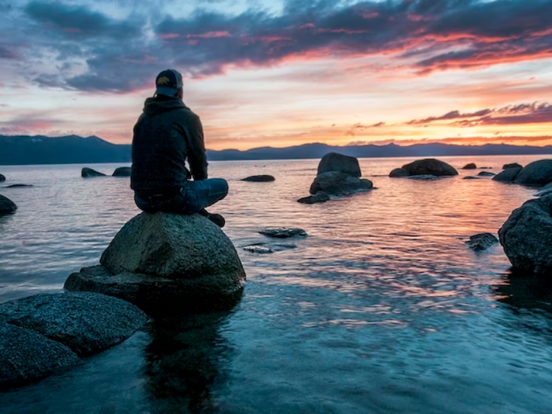 man sitting on rock in water